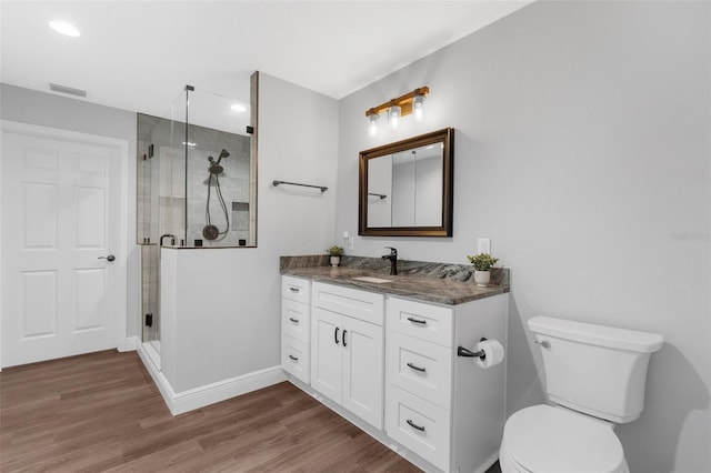 bathroom featuring hardwood / wood-style floors, vanity, an enclosed shower, and toilet