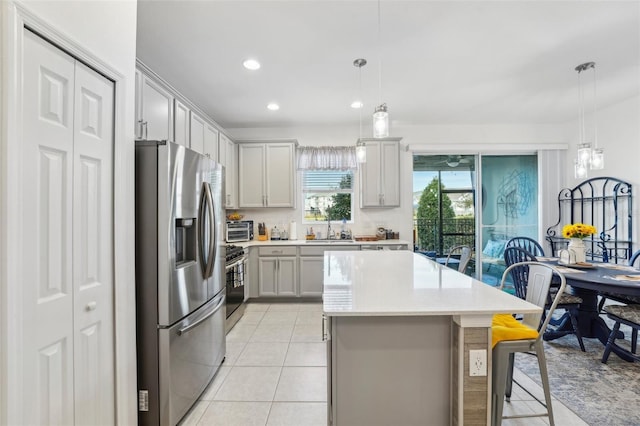 kitchen featuring a breakfast bar, sink, a center island, hanging light fixtures, and appliances with stainless steel finishes