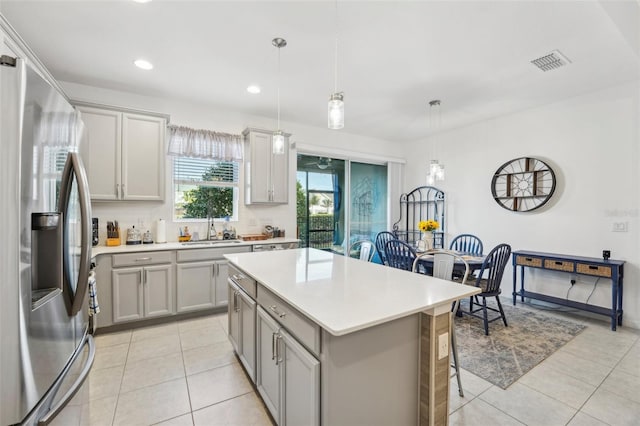 kitchen featuring gray cabinets, a kitchen island, decorative light fixtures, sink, and stainless steel fridge with ice dispenser