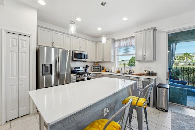 kitchen featuring pendant lighting, sink, appliances with stainless steel finishes, a kitchen island, and decorative backsplash