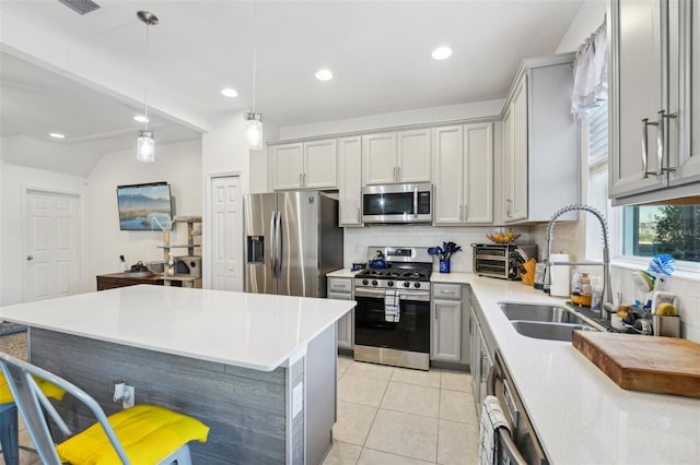 kitchen featuring pendant lighting, sink, gray cabinets, stainless steel appliances, and tasteful backsplash