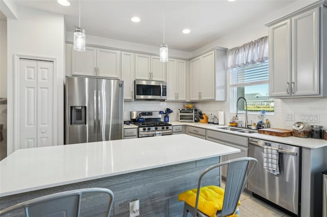 kitchen with pendant lighting, sink, tasteful backsplash, and appliances with stainless steel finishes