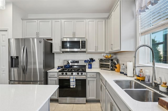 kitchen featuring stainless steel appliances, light tile patterned flooring, sink, and decorative backsplash