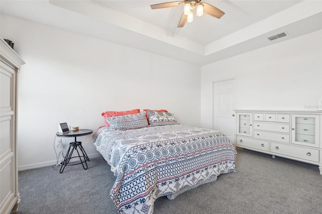 carpeted bedroom with ceiling fan and a raised ceiling