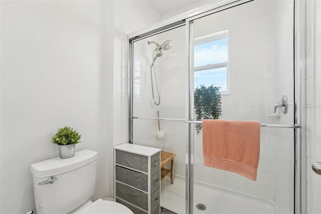 bathroom featuring toilet and a shower with shower door