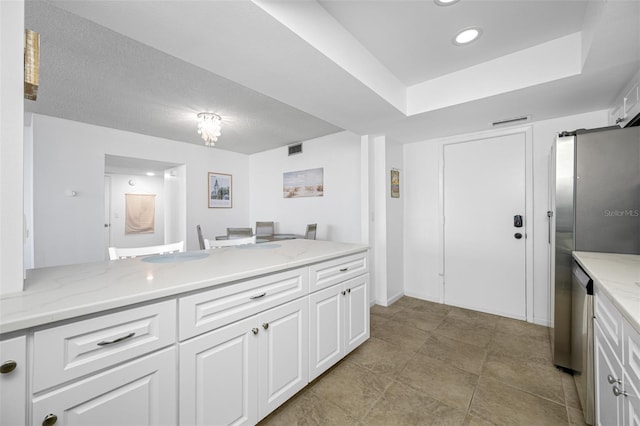 kitchen featuring white cabinetry, light stone counters, and a textured ceiling