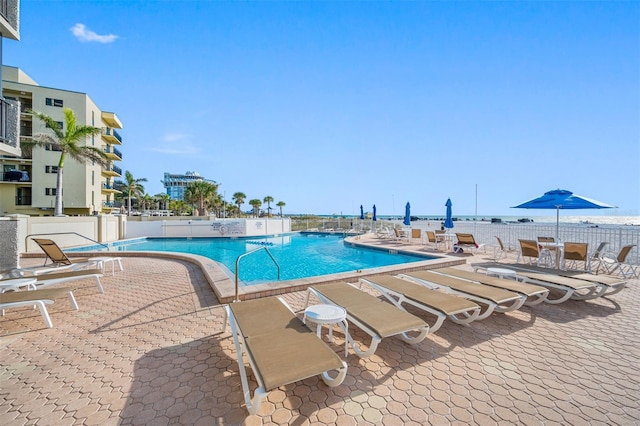 view of swimming pool featuring a water view and a patio area