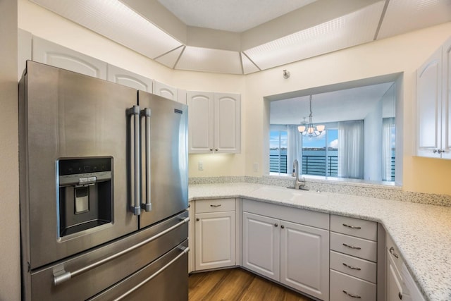 kitchen with stainless steel refrigerator with ice dispenser, sink, white cabinets, and a chandelier