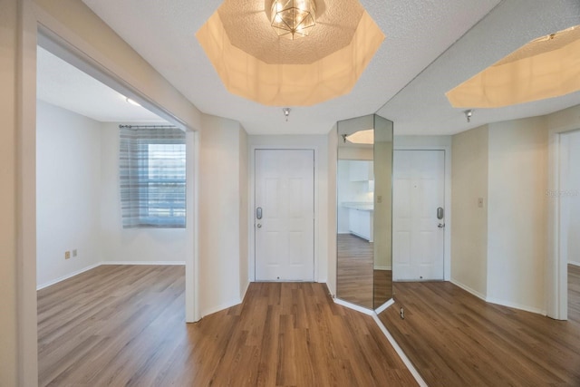 entrance foyer with hardwood / wood-style floors, a textured ceiling, and a tray ceiling