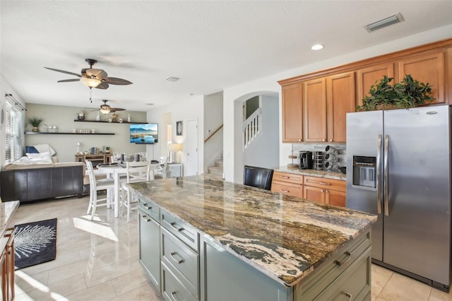 kitchen featuring gray cabinets, a kitchen island, stainless steel refrigerator with ice dispenser, and dark stone counters