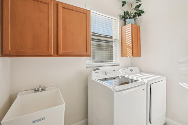 clothes washing area with washer and clothes dryer, cabinets, and sink