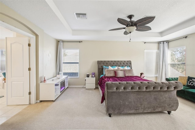 tiled bedroom with a raised ceiling, ceiling fan, and a textured ceiling