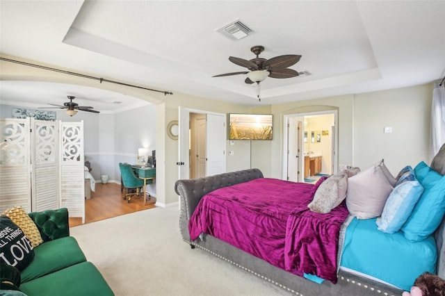 bedroom with a tray ceiling, ceiling fan, ensuite bathroom, and hardwood / wood-style flooring