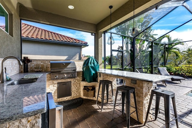 view of patio / terrace featuring glass enclosure, outdoor wet bar, area for grilling, a sink, and a grill