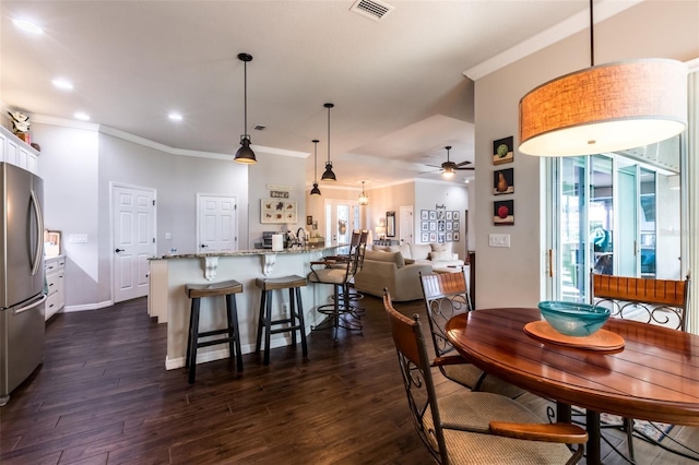 dining room with dark wood-style flooring, visible vents, crown molding, and a healthy amount of sunlight