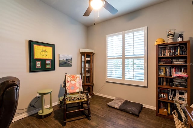 sitting room featuring a ceiling fan, baseboards, and dark wood-style flooring