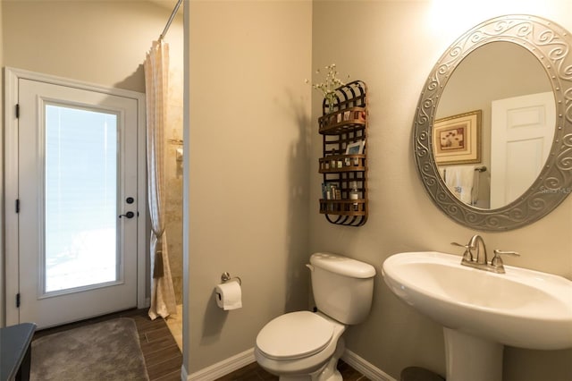 bathroom featuring curtained shower, wood finish floors, toilet, and baseboards