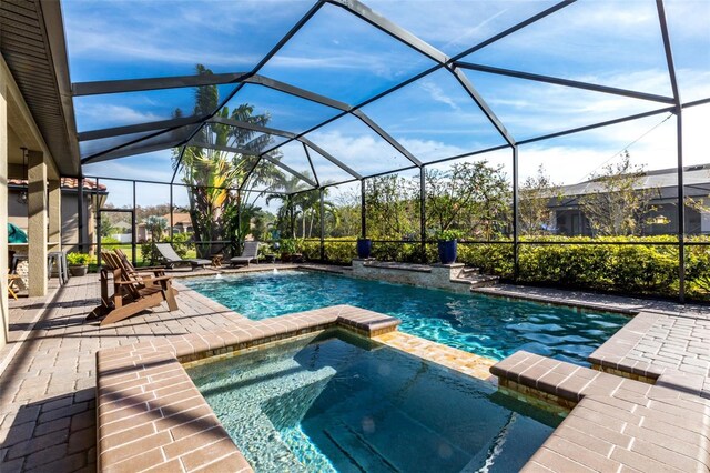 view of pool featuring a pool with connected hot tub, a patio area, and a lanai