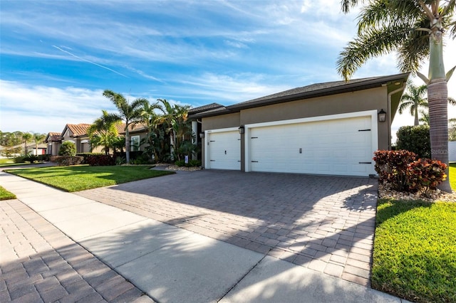 exterior space featuring a garage, a front yard, decorative driveway, and stucco siding