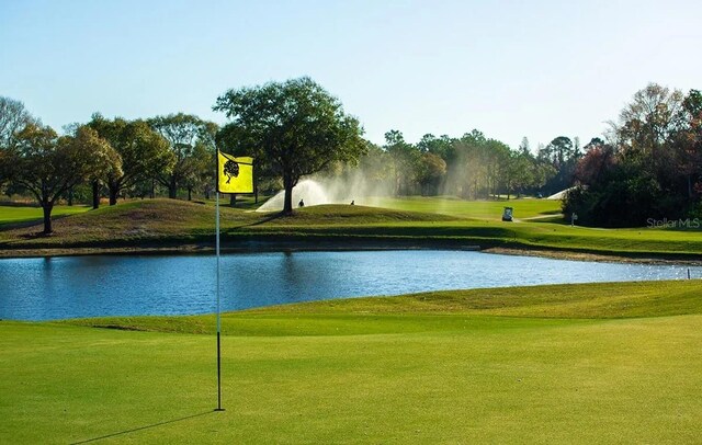 surrounding community featuring a water view, a yard, and golf course view