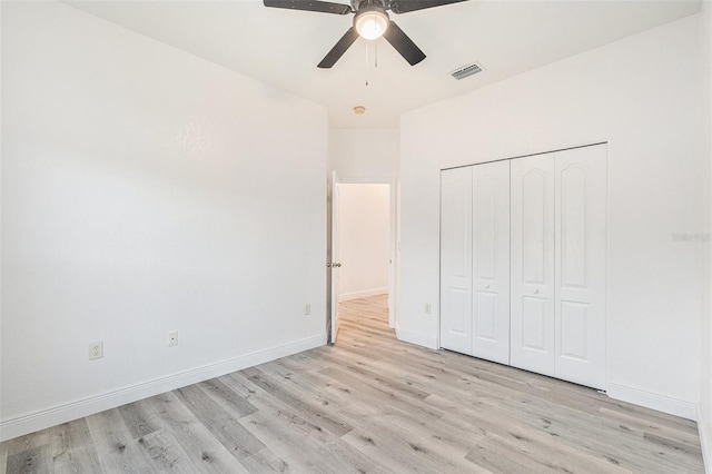 unfurnished bedroom with ceiling fan, light wood-type flooring, and a closet