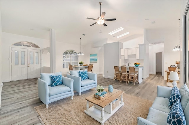 living room featuring ceiling fan with notable chandelier, light hardwood / wood-style floors, lofted ceiling, and sink