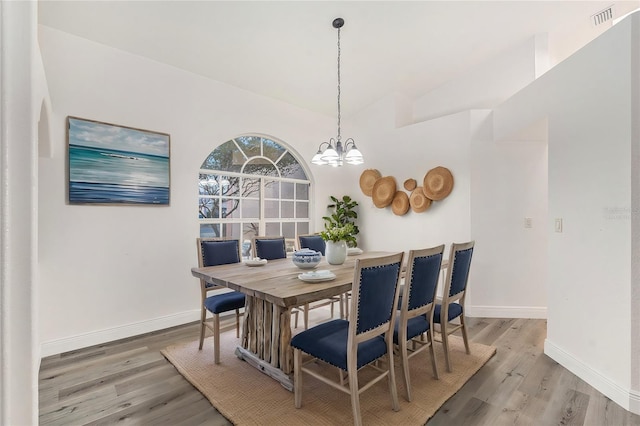 dining room featuring lofted ceiling, hardwood / wood-style flooring, and a notable chandelier