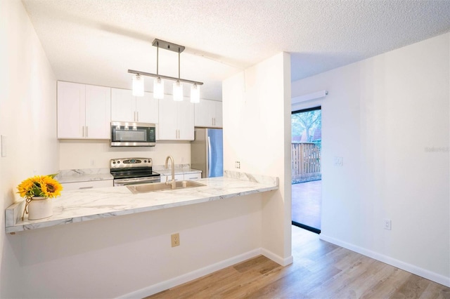 kitchen featuring white cabinetry, kitchen peninsula, appliances with stainless steel finishes, hanging light fixtures, and a textured ceiling