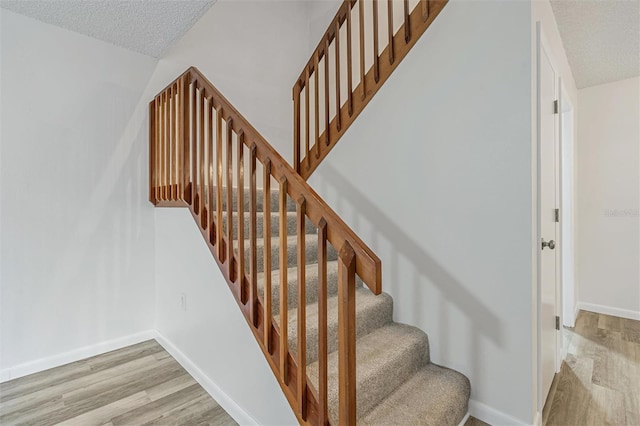 stairway featuring wood-type flooring and a textured ceiling