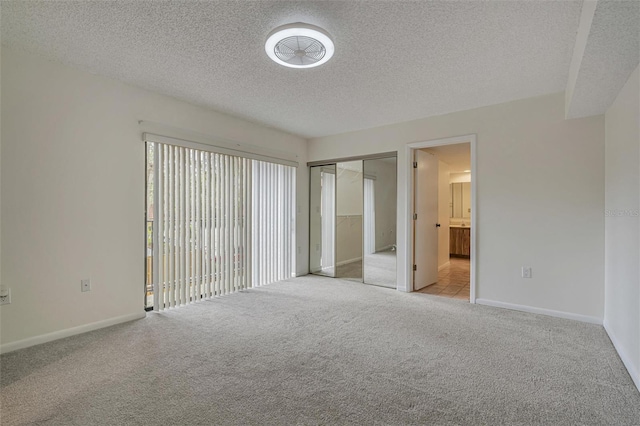 spare room featuring light carpet and a textured ceiling