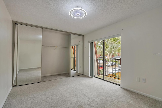 unfurnished bedroom featuring light carpet, a closet, access to outside, and a textured ceiling