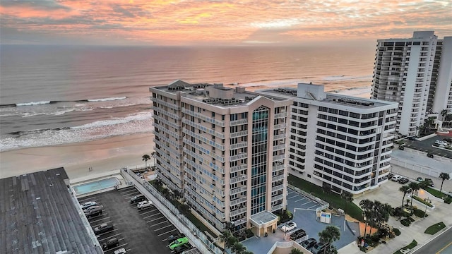 aerial view at dusk with a water view and a view of the beach