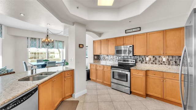 kitchen with sink, light stone counters, pendant lighting, a chandelier, and appliances with stainless steel finishes