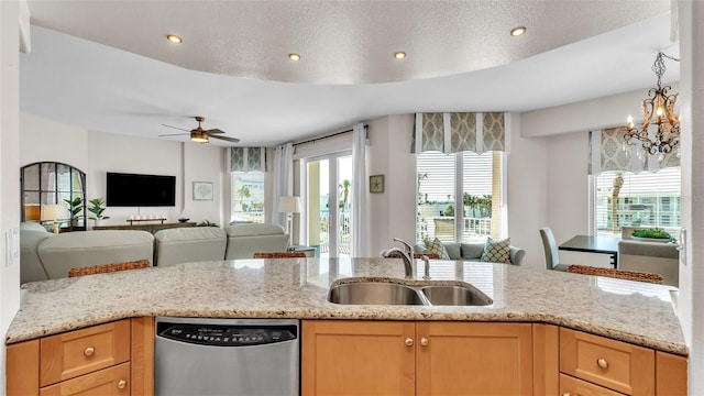 kitchen featuring stainless steel dishwasher, light stone countertops, and sink