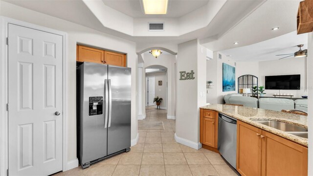 kitchen with sink, ceiling fan, light tile patterned flooring, light stone counters, and stainless steel appliances