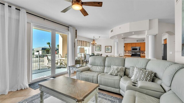 tiled living room with ceiling fan with notable chandelier