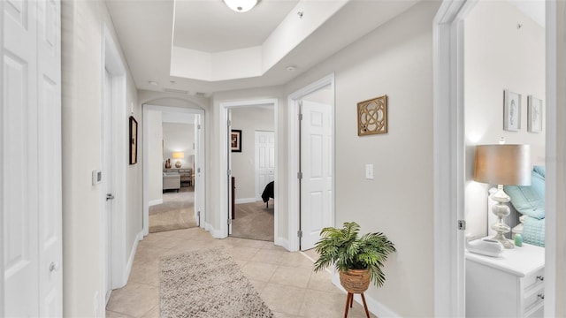 corridor with a tray ceiling and light carpet