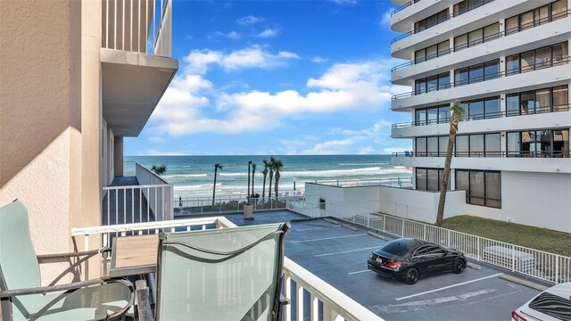 balcony with a water view and a view of the beach