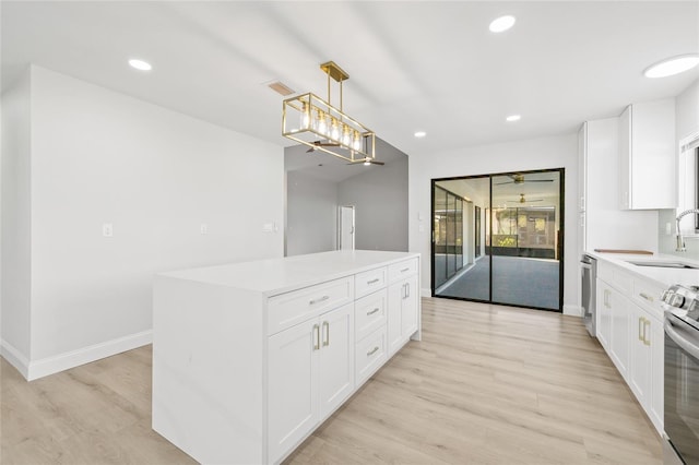 kitchen with a center island, white cabinets, sink, hanging light fixtures, and appliances with stainless steel finishes