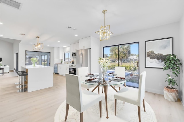 dining space featuring light hardwood / wood-style floors, sink, and an inviting chandelier