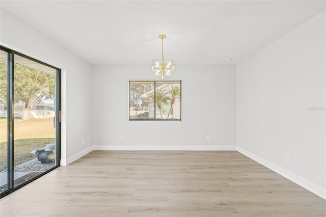 unfurnished room featuring a chandelier and light hardwood / wood-style floors