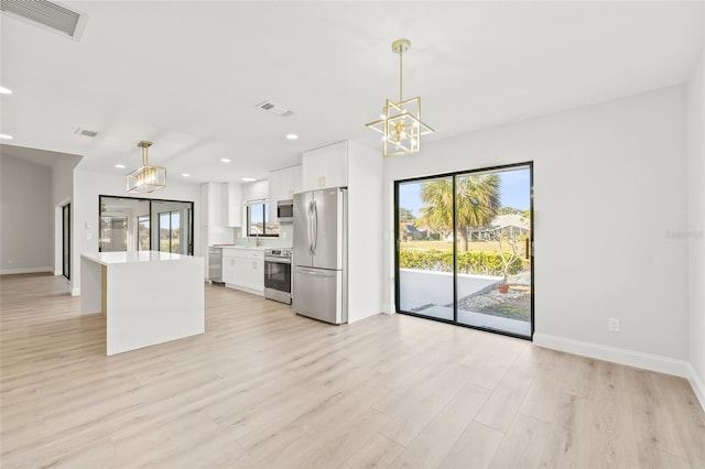 kitchen with a center island, light hardwood / wood-style flooring, decorative light fixtures, white cabinetry, and stainless steel appliances