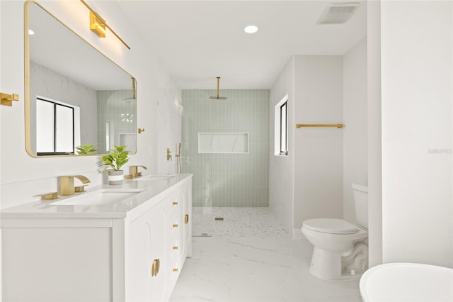 bathroom with a tile shower, vanity, and toilet