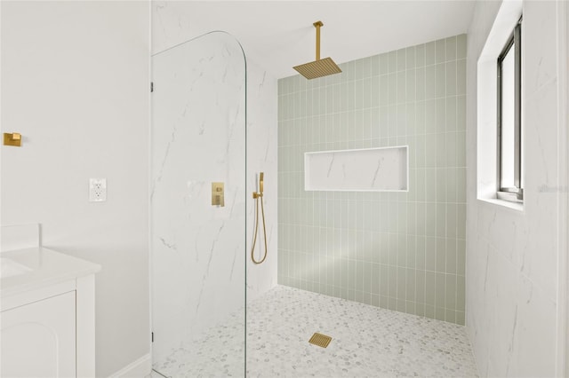 bathroom with a tile shower and vanity