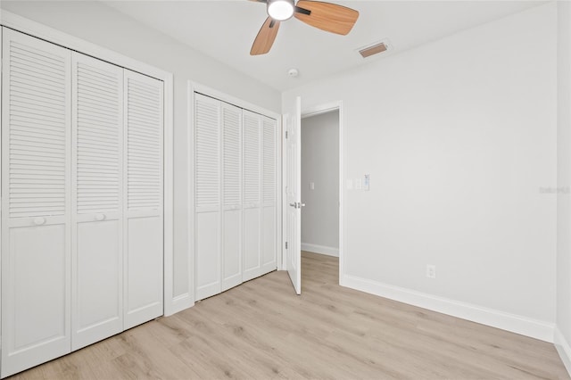 unfurnished bedroom with light hardwood / wood-style flooring, ceiling fan, and multiple closets