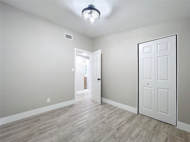 unfurnished bedroom featuring light wood-type flooring and a closet