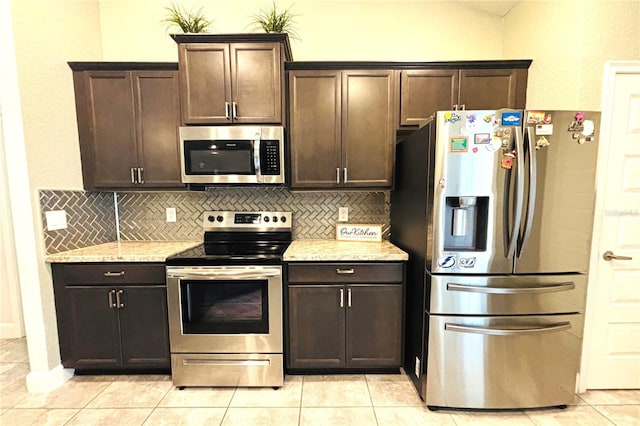 kitchen with light stone countertops, dark brown cabinetry, backsplash, and appliances with stainless steel finishes