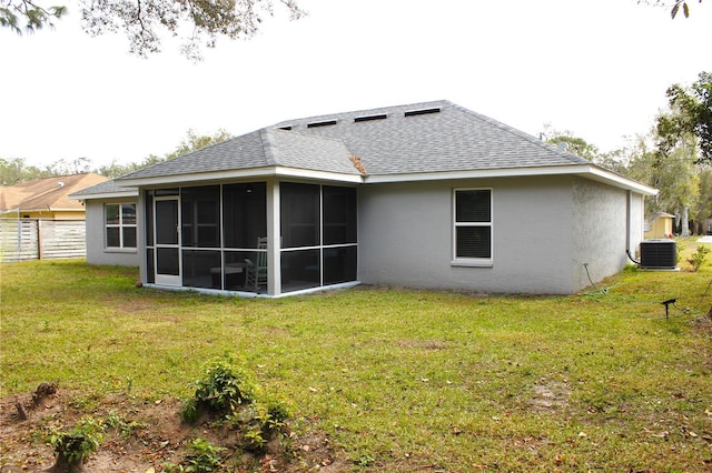 rear view of house with a yard, central AC, and a sunroom