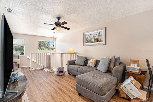 living room featuring ceiling fan, wood-type flooring, and a textured ceiling