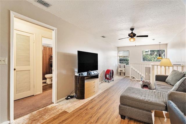 living room with ceiling fan, hardwood / wood-style floors, and a textured ceiling